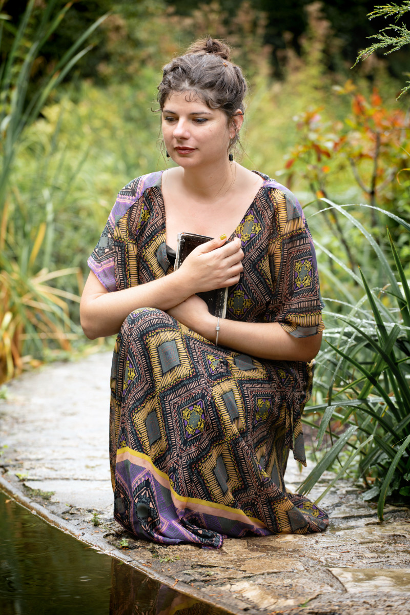 Une femme assise près de l'eau qui pense à ses prochaines histoires